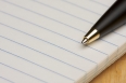 Pen and Pad of Lined Paper on a Wood Background