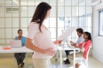 Pregnant worker touches belly and looks at file in the office
