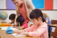 Cute pupils writing at desk in classroom at the elementary school