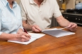 Senior couple reading and writing at home in the kitchen