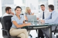 Young businesswoman with colleagues discussing in background at a bright office