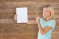 Angry woman holding piece of paper against wooden planks background