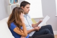 Stressed couple sitting on couch and paying their bills in the living room at home