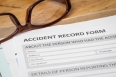 Accident report application form on brown envelope and eyeglass,